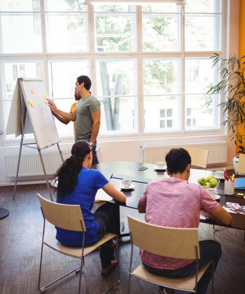 business executives discussing with their colleagues on whiteboard