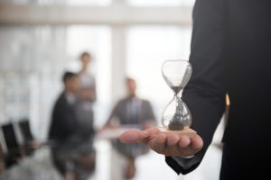 businessman holding an hour glass, signifies the importance of being on time